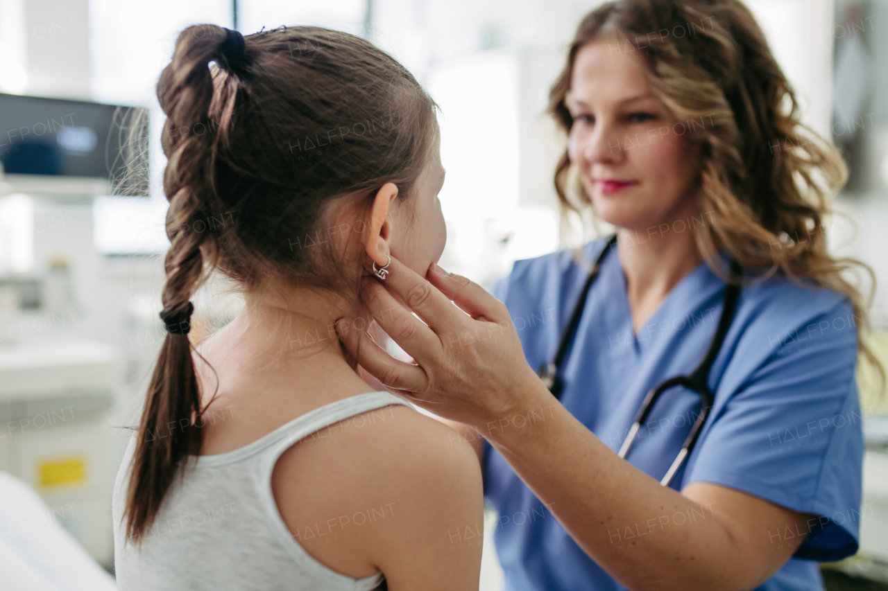 Female doctor examining lymp nodes on neck of the young girl. Palpation of lymph nodes. Concept of preventive health care for childre