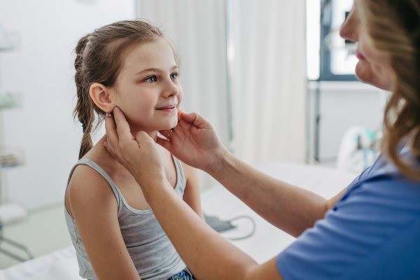 Female doctor examining lymp nodes on neck of the young girl. Palpation of lymph nodes. Concept of preventive health care for childre