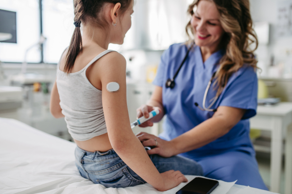 Nurse injecting insulin in diabetic young girl belly. Close up of young girl with type 1 diabetes taking insuling with syringe needle.