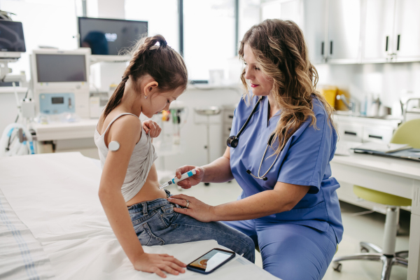 Nurse injecting insulin in diabetic young girl belly. Close up of young girl with type 1 diabetes taking insuling with syringe needle.