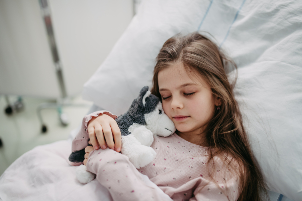 Little girl patient lying in hospital bed. Children in intensive care unit in hospital sleeping. Banner with copy space.