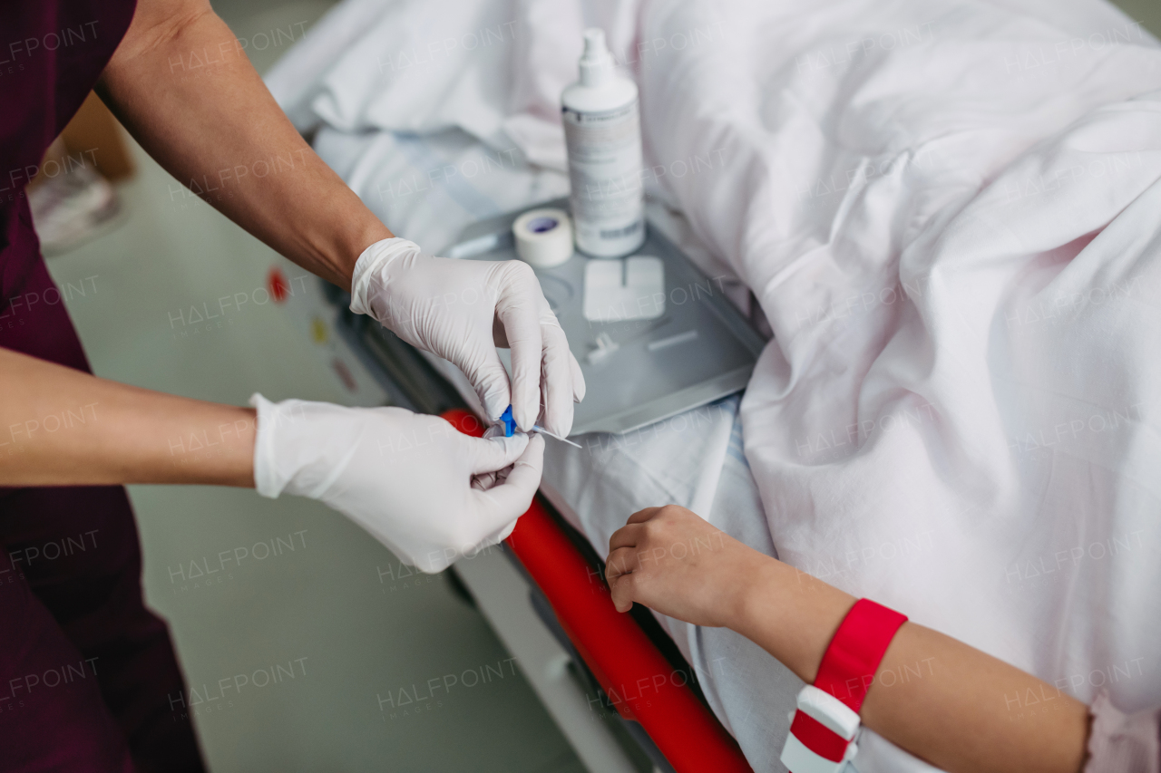 Close up of nurse insering IV cannula in vein, hand of little girl. IV, intravenous therapy for child patient.