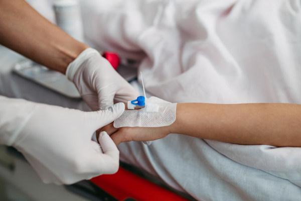 Close up of nurse insering IV cannula in vein, hand of little girl. IV, intravenous therapy for child patient.