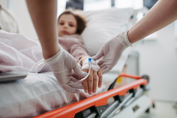 Close up of nurse insering IV cannula in vein, hand of little girl. IV, intravenous therapy for child patient.