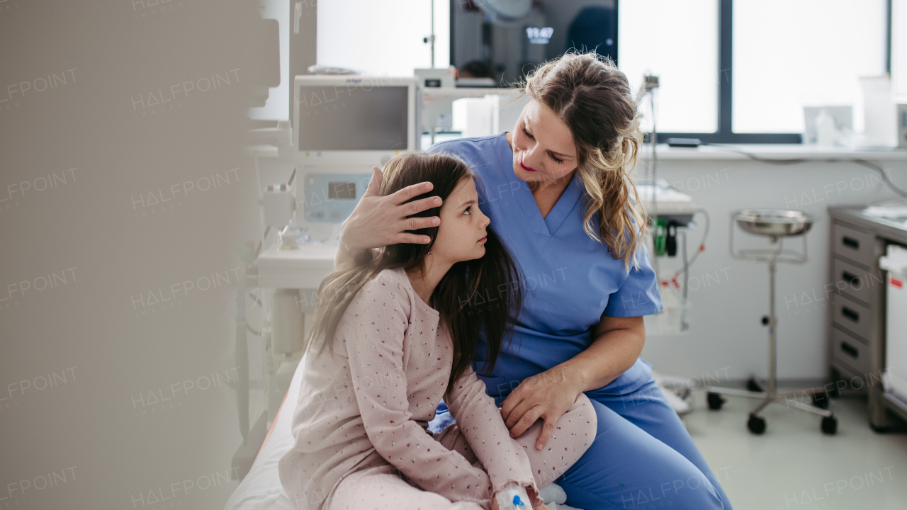 Supportive doctor soothing a worried girl patient in emergency room. Concept of emotional support and friendliness for young kid patient.