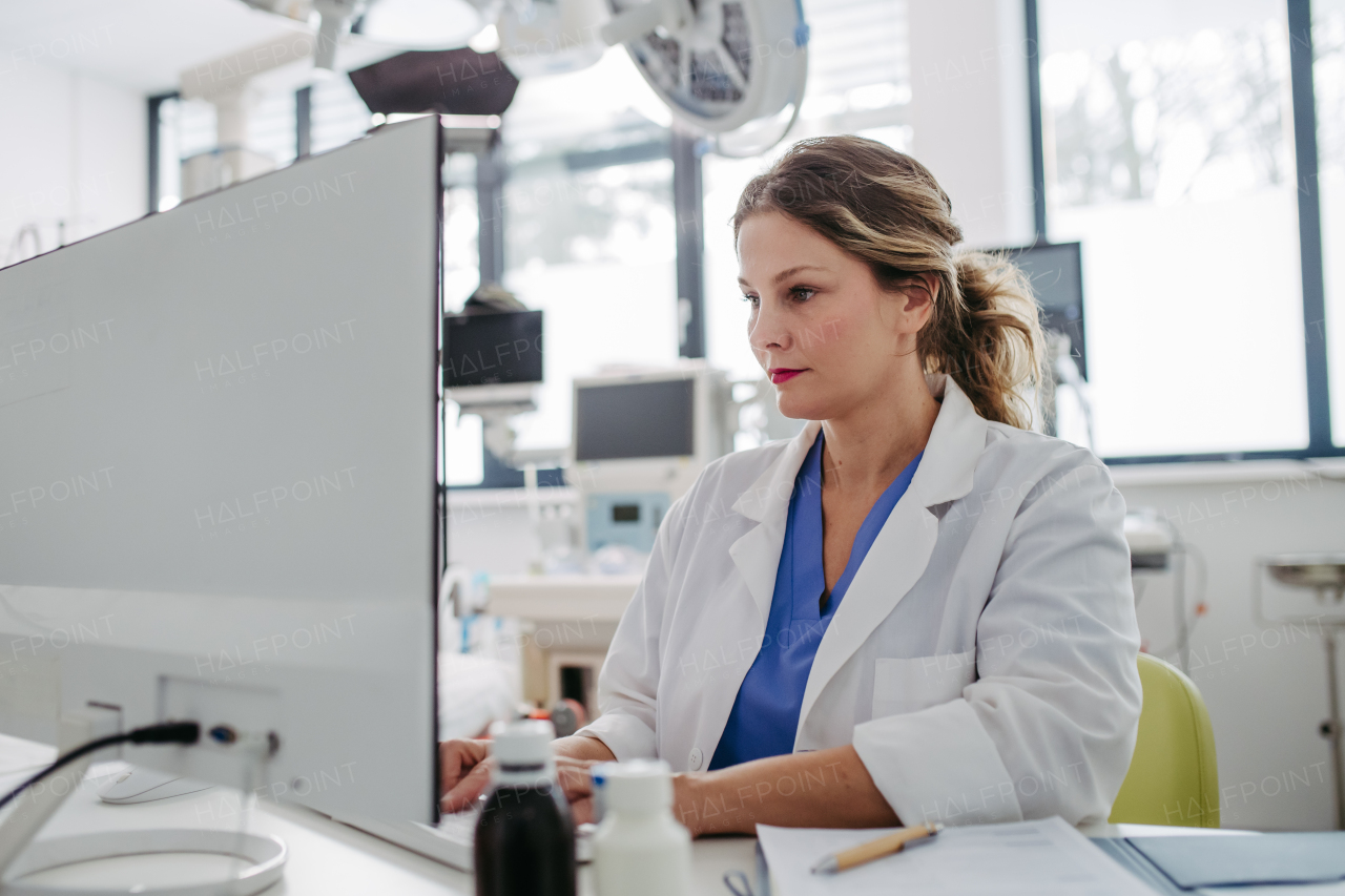 Female doctor working on computer in doctor's office, looking at MRI scan, test results of patient. Doctor consulting scan with the other doctors.