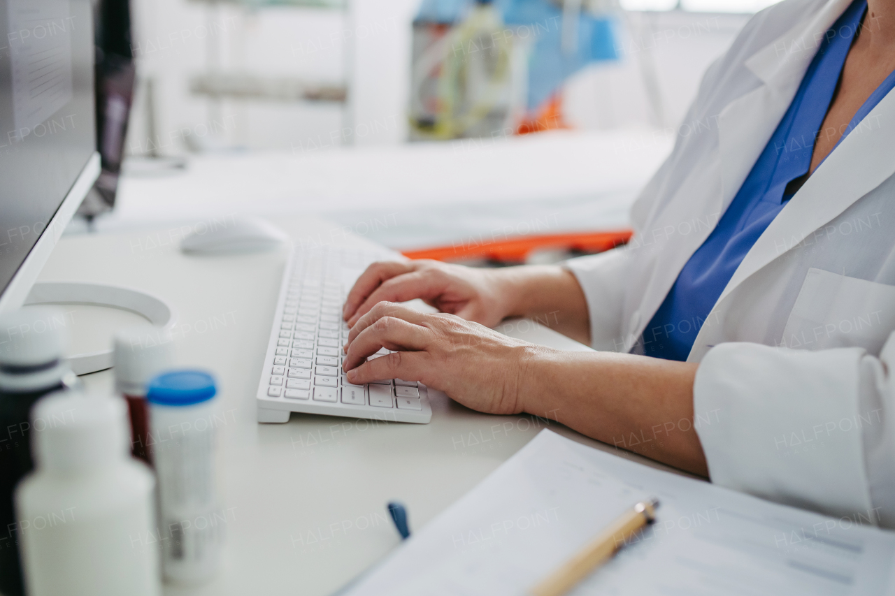 Female doctor working on computer in doctor's office, looking at MRI scan, test results of patient. Doctor consulting scan with the other doctors.