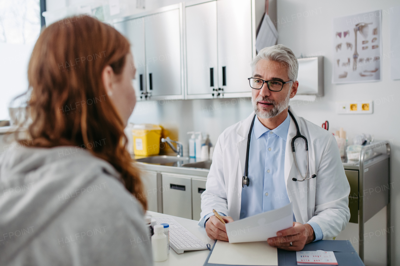 Doctor discussing test results with teenage girl, explaining her diagnosis and medication usage. Concept of preventive health care for adolescents.