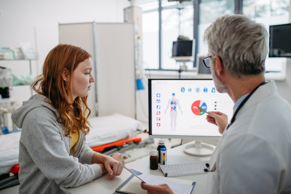 Teenage girl explaining her health problems, pain. headache. Doctor showting medical test results. Concept of preventive health care for adolescents.