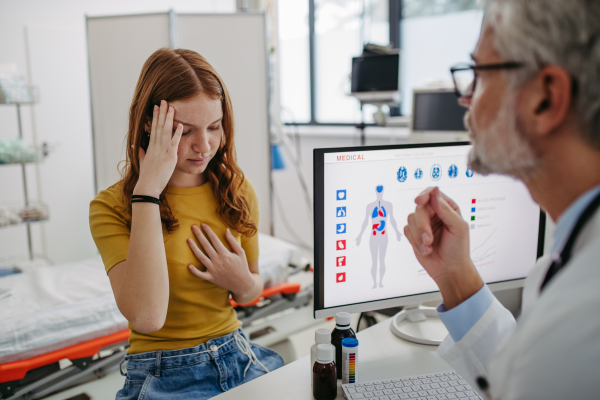 Teenage girl explaining her health problems, pain. headache. Sick girl patient in doctors office. Concept of preventive health care for adolescents.