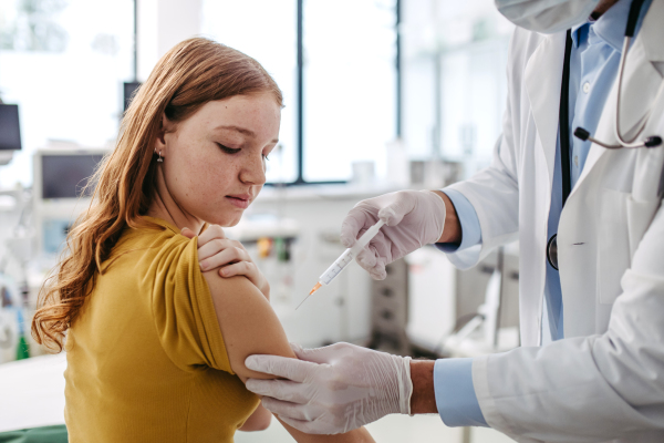 Doctor, pediatrician injecting vaccine into teenage girl arm. Concept of preventive health care and vaccination for teenagers, immunisation.