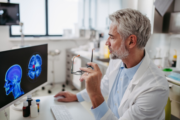 Portrait of sad doctor looking at an MRI scan, patient's bad test results, feeling helpless. Recurrence of the disease