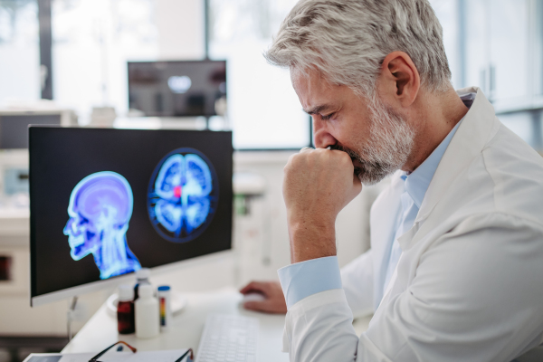 Portrait of sad doctor looking at an MRI scan, patient's bad test results, feeling helpless. Recurrence of the disease