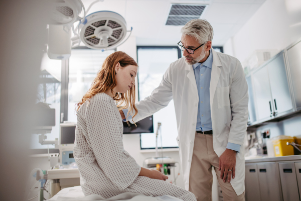 Doctor delivering bad news to teenage patient in hospital, discussing her test result in emergency room.