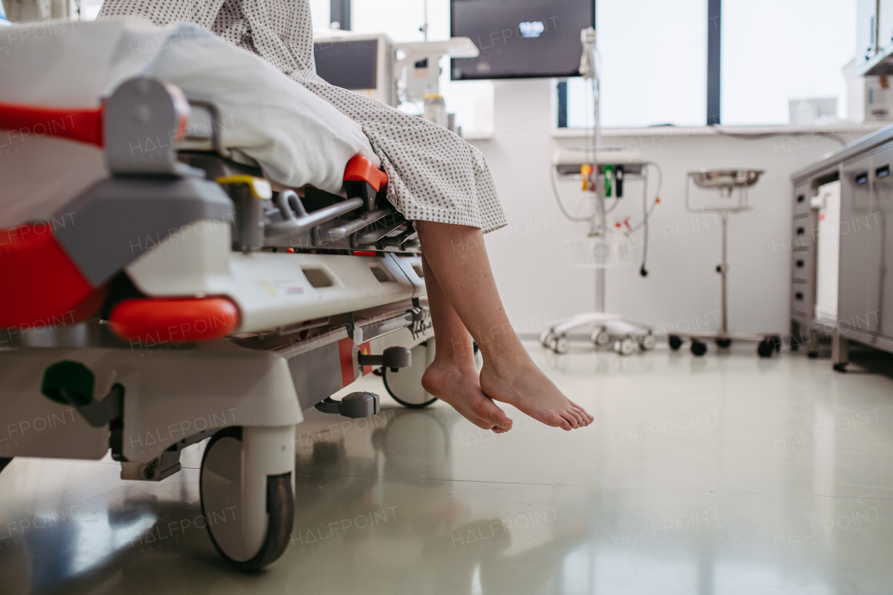 Close up of barefoot legs of patient, sitting on hospital bed in emergency room. Anxiety, worry and loneliness of patient in the hospital.