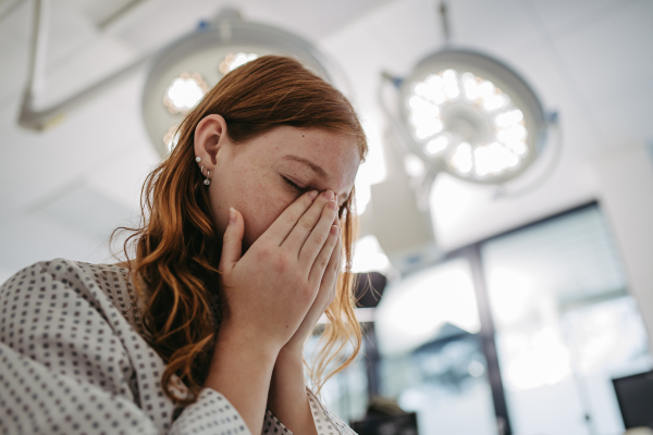 Close up of scared teenage patient, waitng for test results. Anxiety, worry and loneliness of teenager in hospital. Emotional support for ill young girl.