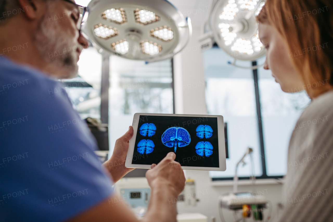 Doctor showing girl teenage patient MRI scan on tablet, discussing test result in emergency room.