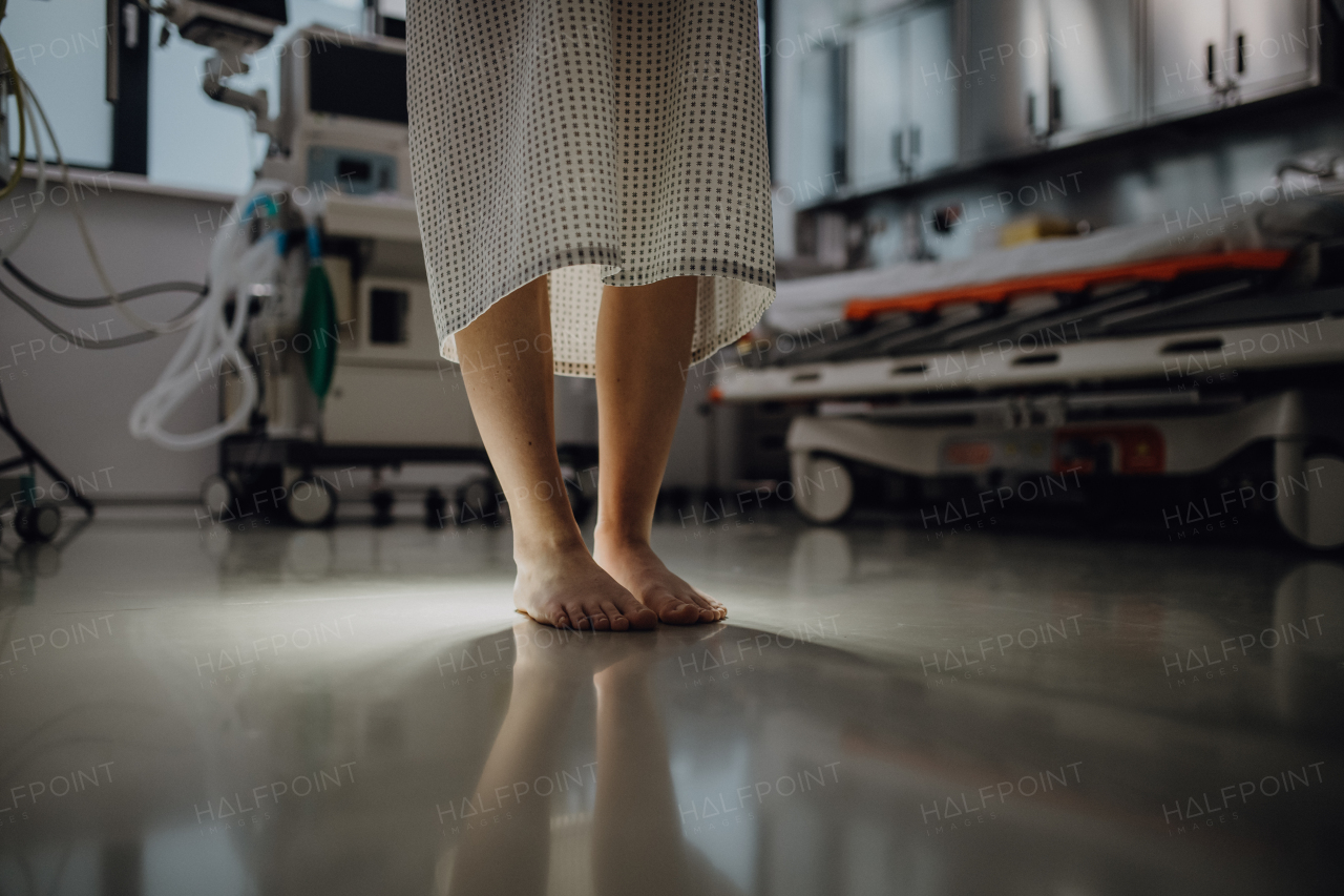 Close up of barefoot legs of patient, standing by hospital bed in emergency room. Anxiety, worry and loneliness of patient in the hospital.