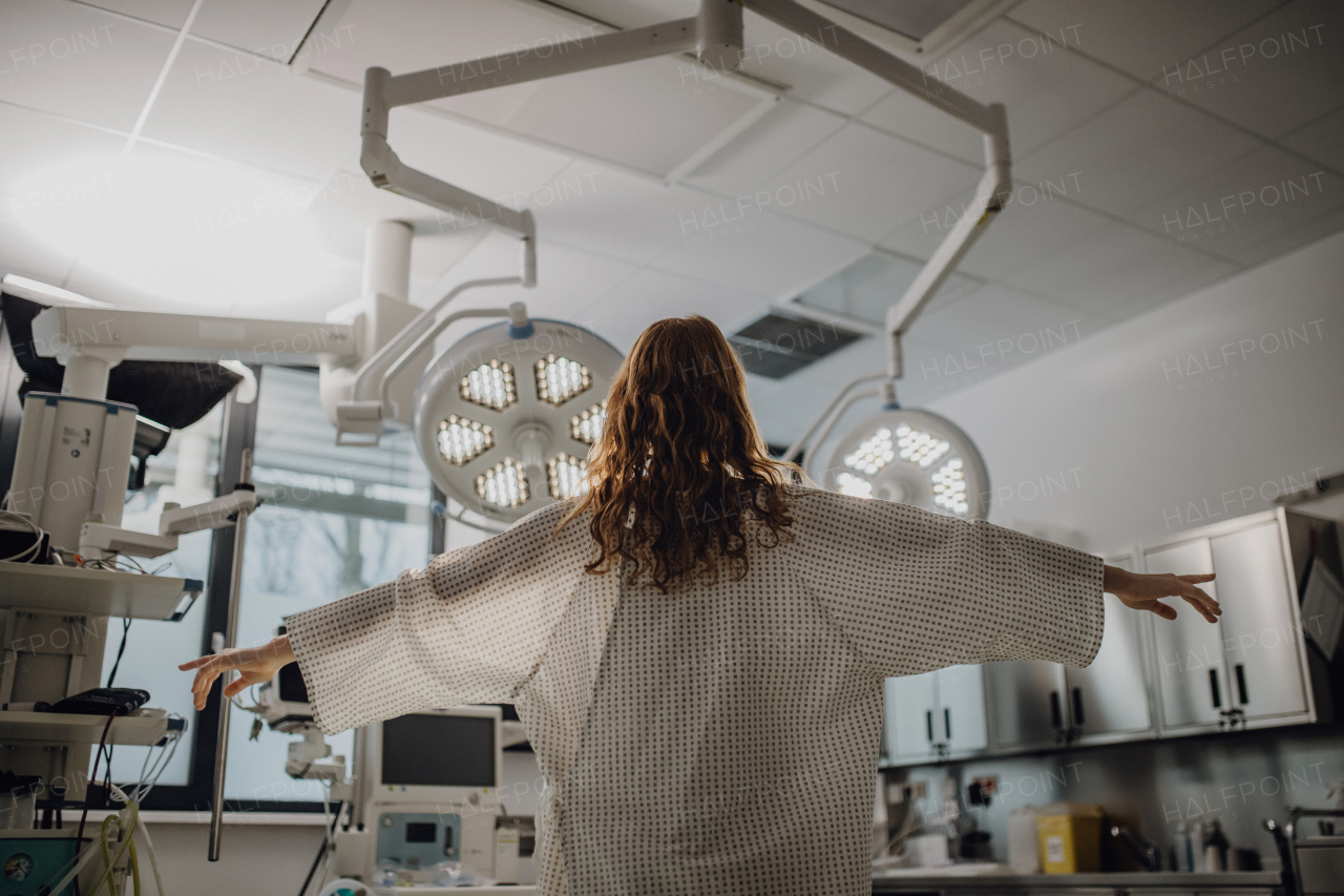 Rear view of patient in hospital gown in emergency room in hospital. Looking like angel.