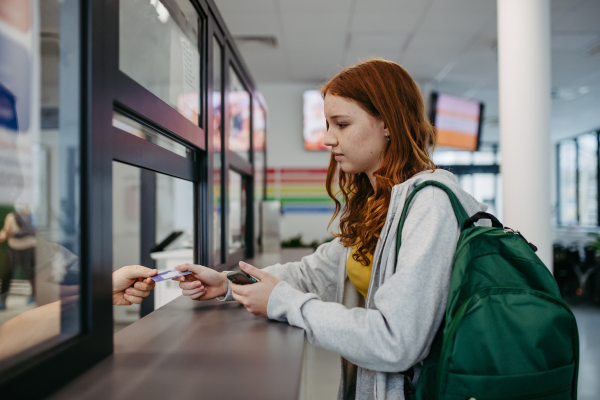 Teenage girl showing her ID card to receptionist in the hospital. Coming to hospital for examination.