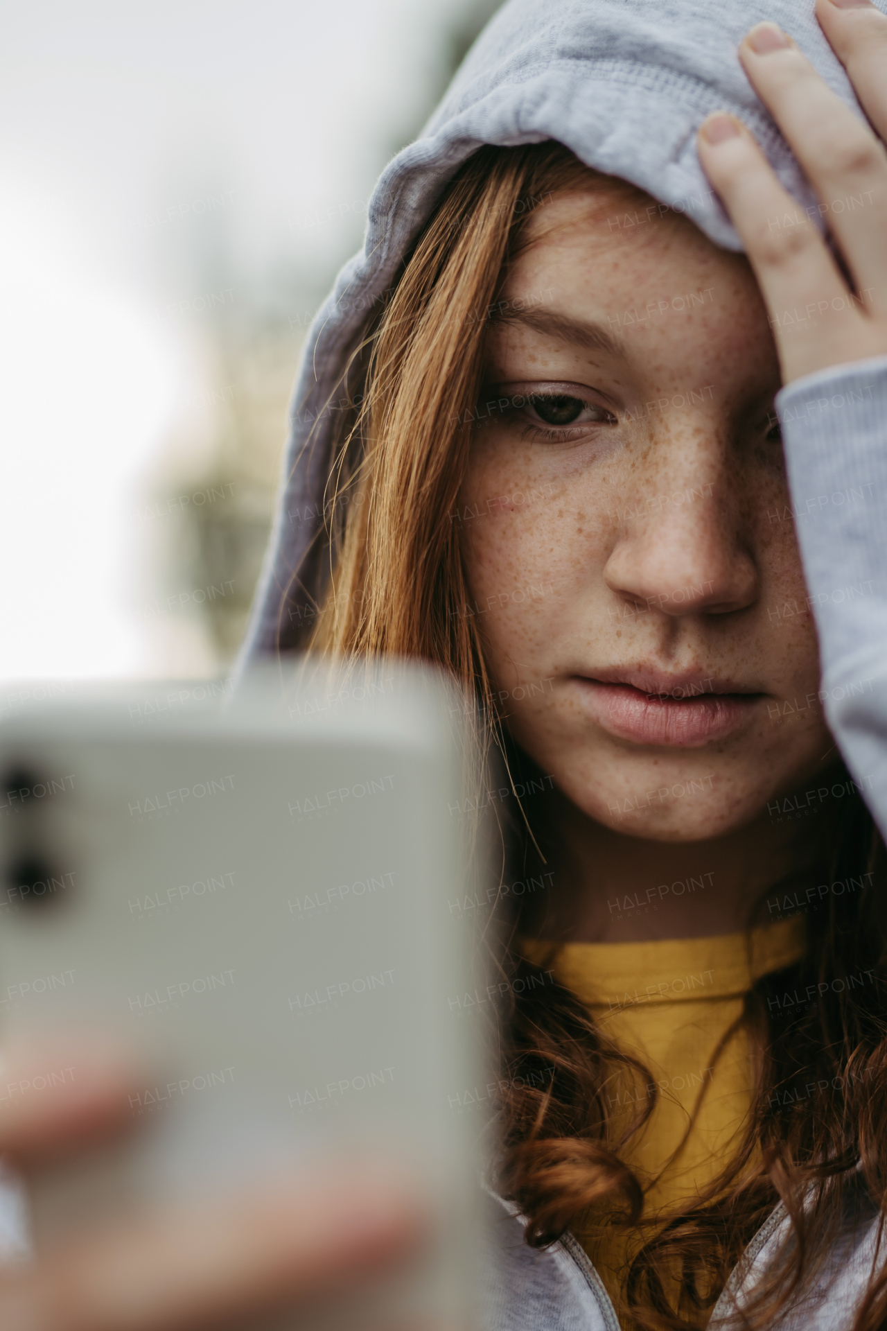 Portrait of teenage girl looking at her smartphone, feeling sad, anxious, alone. Cyberbullying, girl is harassed, threated online.