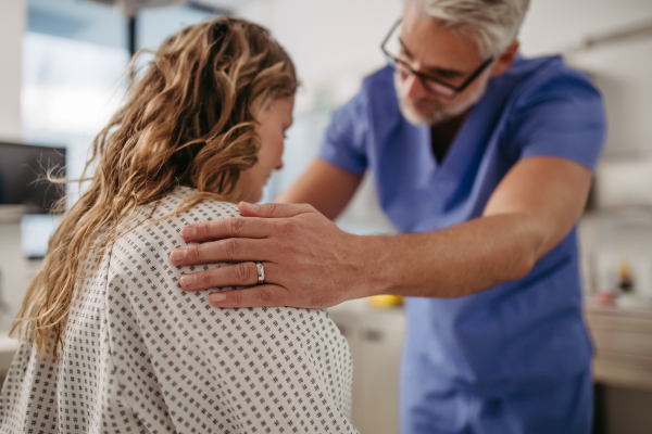 Doctor showing female patient MRI scan on tablet, discussing her test result in emergency room.