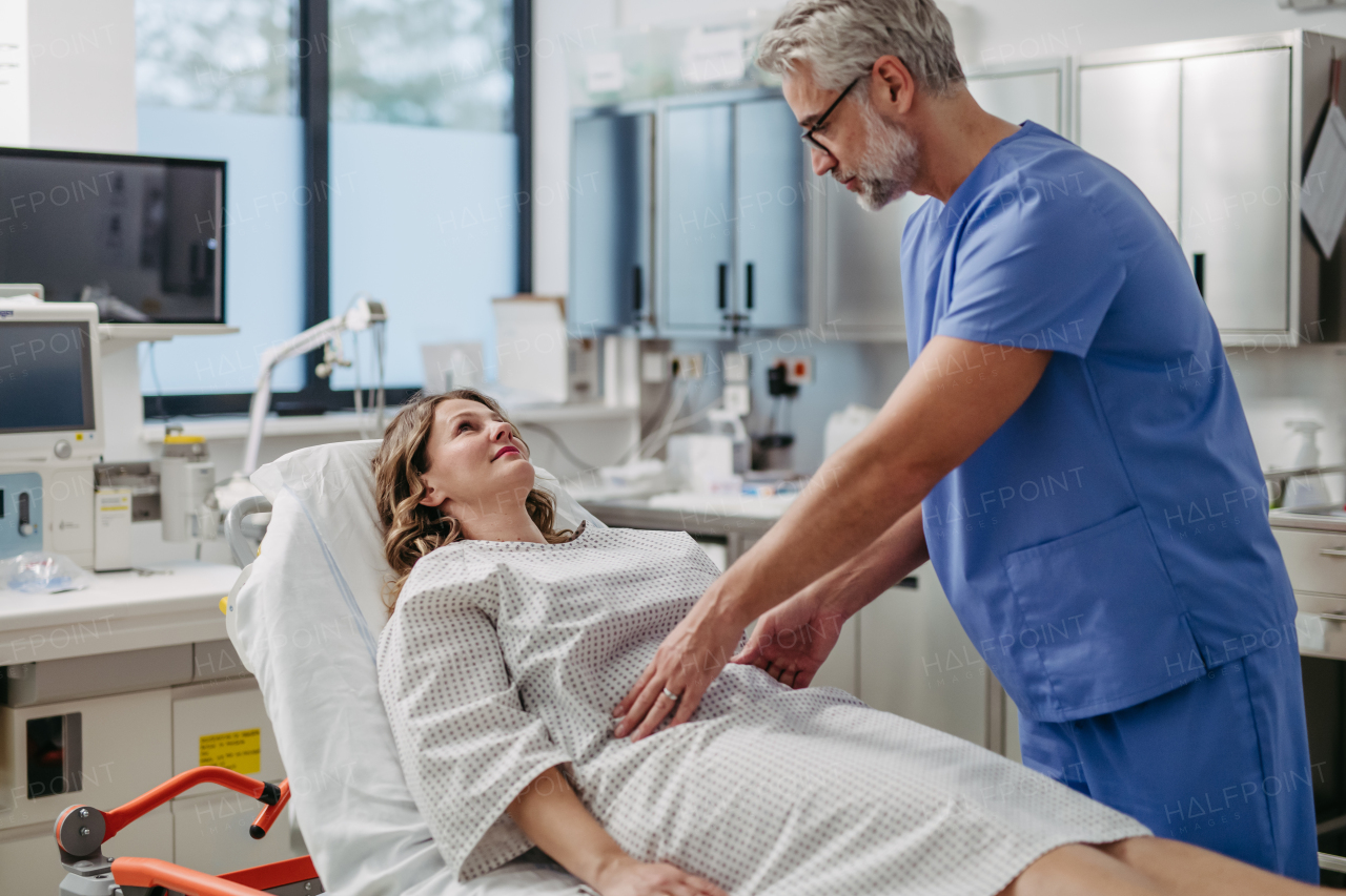 ER doctor palpating woman's abdomen, using hands and steady pressure.