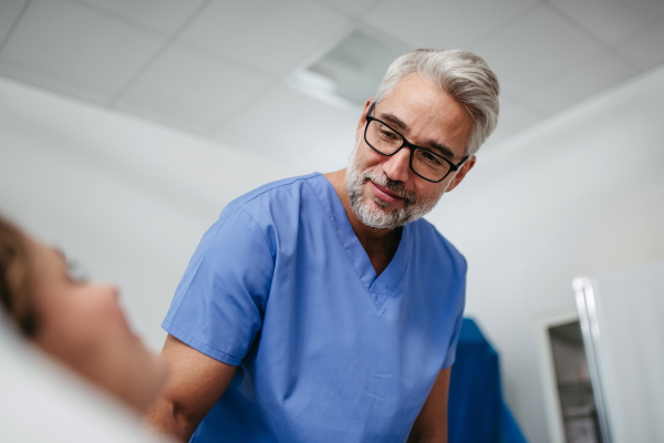 Portrait of handsome doctor talking with worried patient, emotional support before surgery. Friendly male doctor reassuring the patient. Low angle shot.