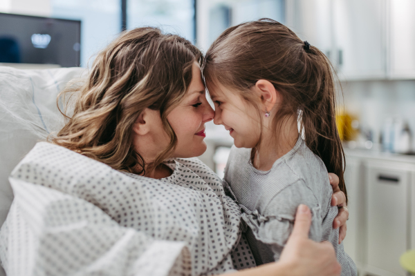 Daughter visiting mother in hospital after successful surgery, hugging her. Emotional support from family for patients in hospital.