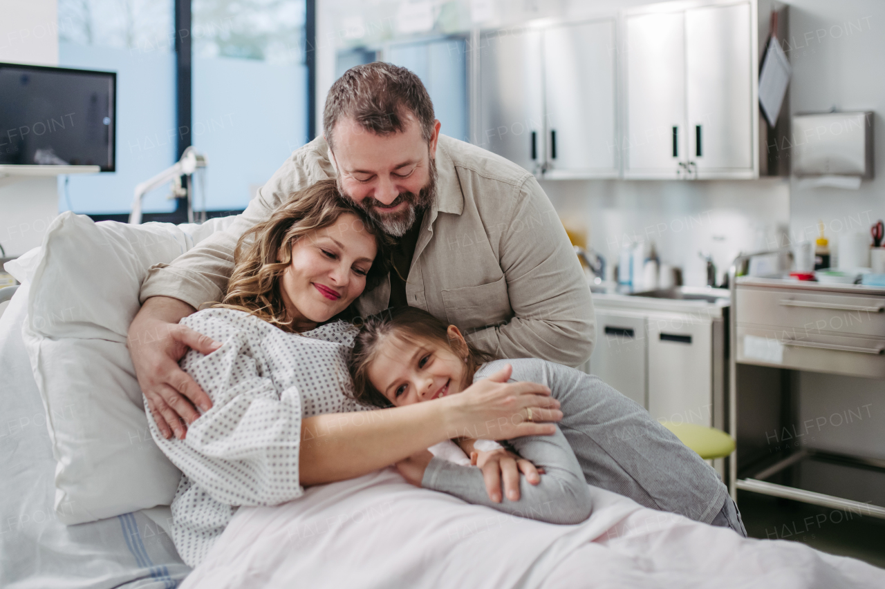 Father and daughter visiting mother in hospital after successful surgery. Emotional support from family for patients in hospital.