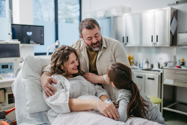 Father and daughter visiting mother in hospital after successful surgery. Emotional support from family for patients in hospital.