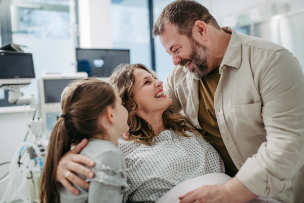 Father and daughter visiting mother in hospital after successful surgery. Emotional support from family for patients in hospital.