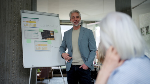 Businessman giving a presentation in a business meeting. Young colleagues and manager having casual discussion during meeting, workshop in office.