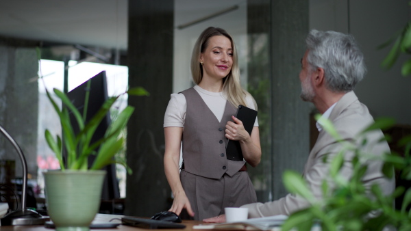 A male manager talking with his employee in modern office. Company director is happy, satisfied for workers quality work.