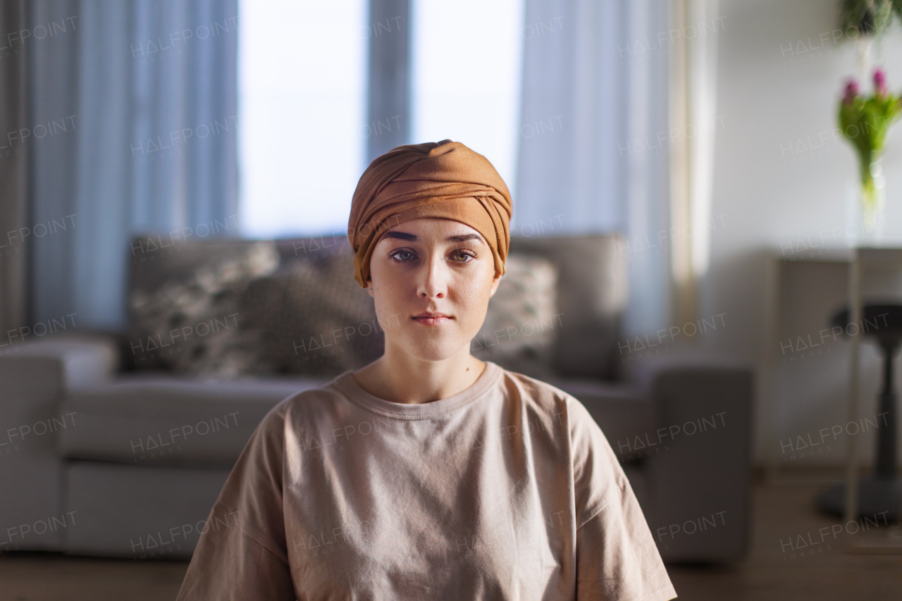 Portrait of young woman with cancer sitting in the apartment.