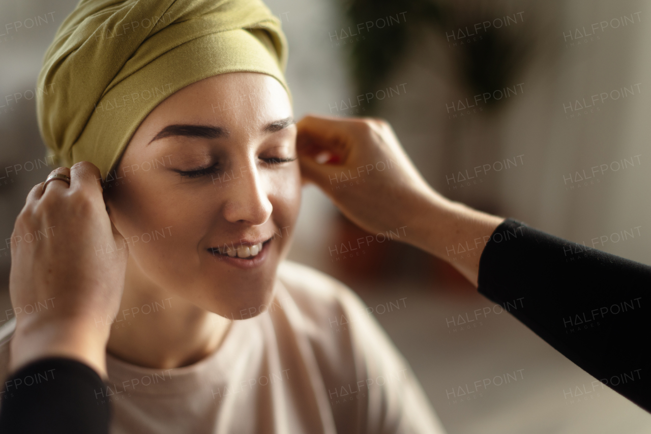 Somebody giving sfarf on head to a young woman with cancer, concept of support.