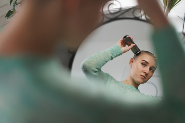 Young woman shaving hair before chemotherapy.