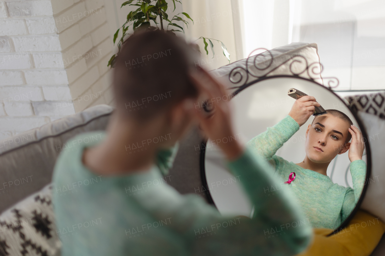 Young woman shaving hair before chemotherapy.