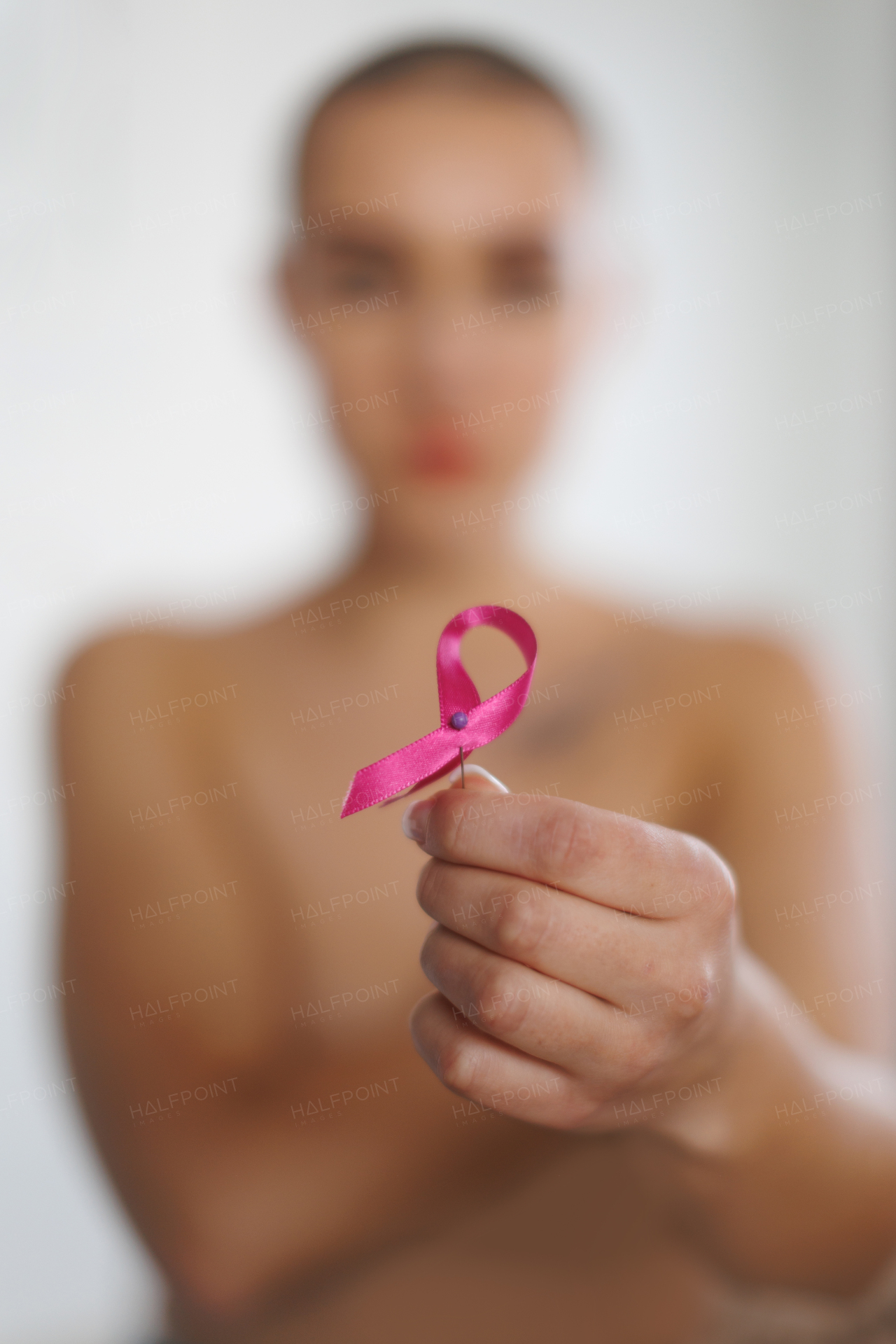 Close-up of woman holding a pink ribbon, concept of breast cancer awareness.