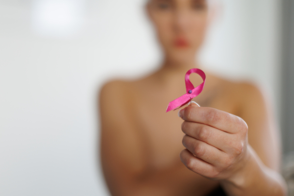 Close-up of woman holding a pink ribbon, concept of breast cancer awareness.