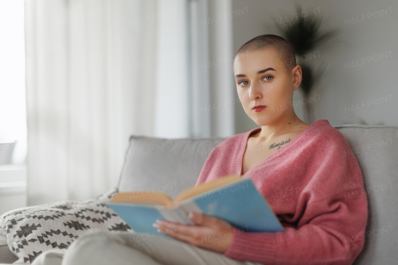 Young woman with cancer reading a book, cancer awareness concept.