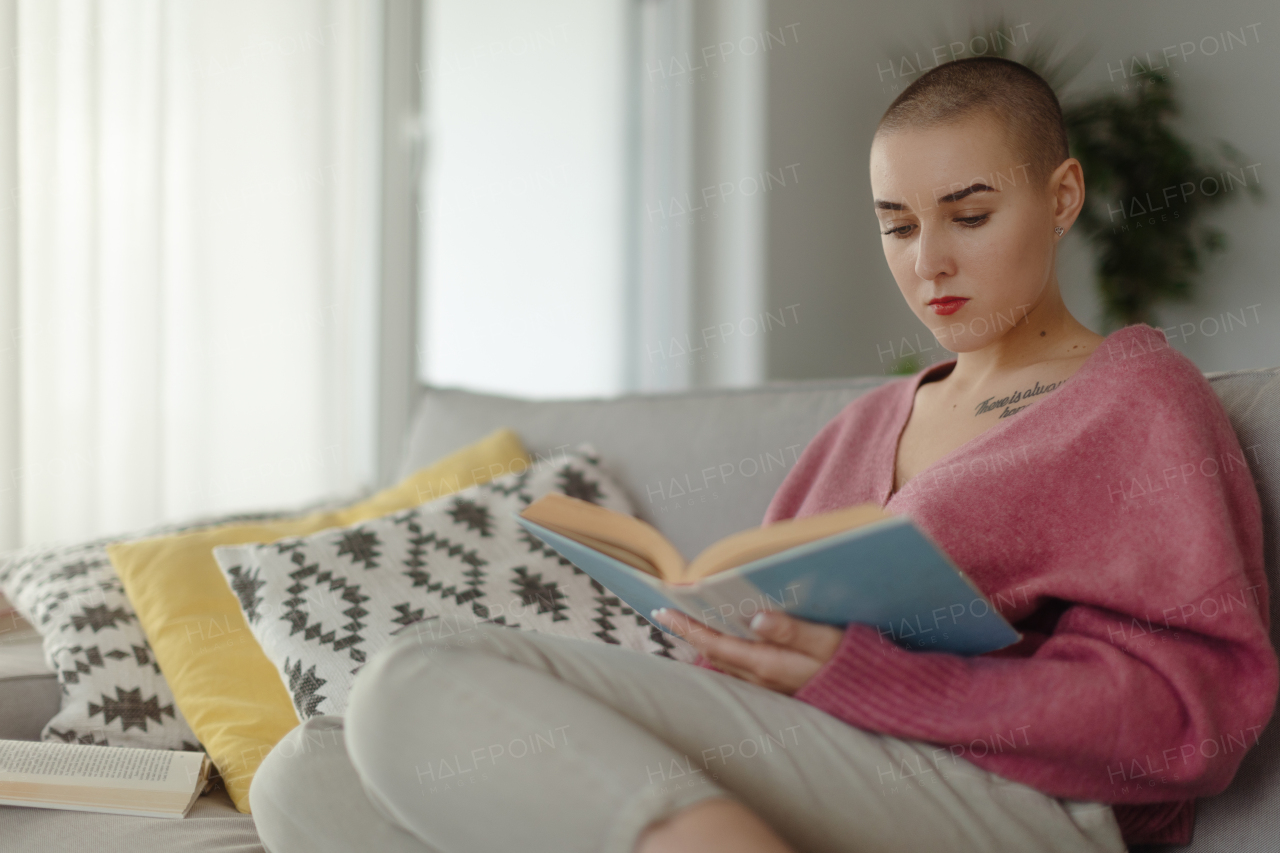 Young woman with cancer reading a book, cancer awareness concept.