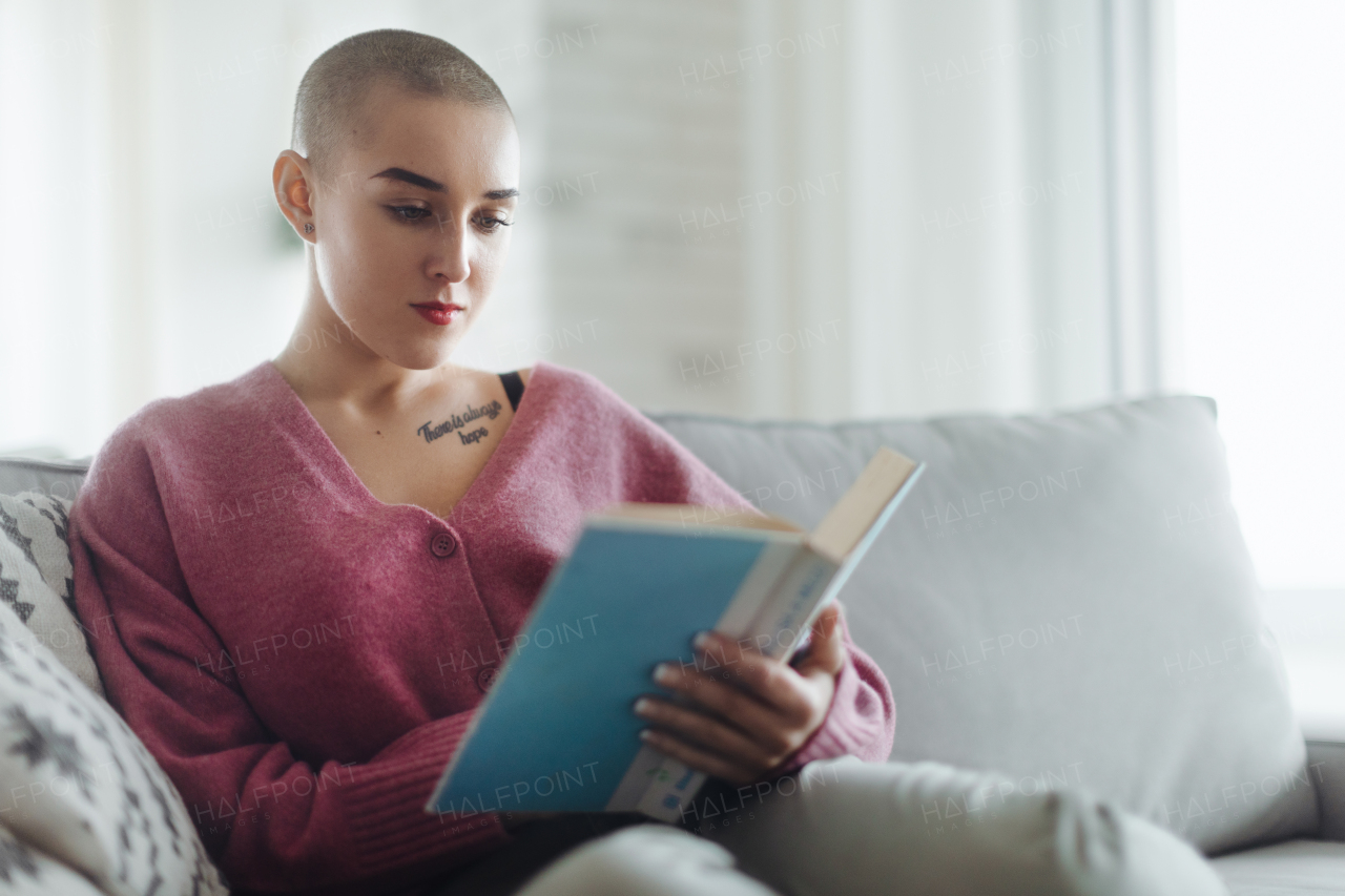 Young woman with cancer reading a book, cancer awareness concept.