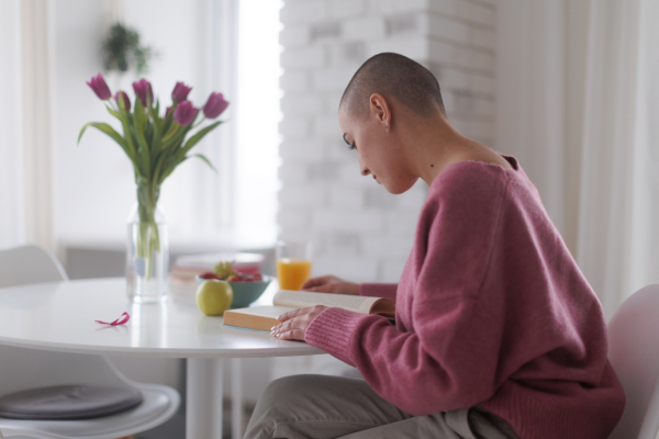 Young woman with cancer reading a book, cancer awareness concept.