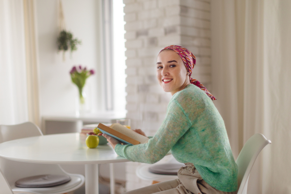 Young woman with cancer reading a book, cancer awareness concept.