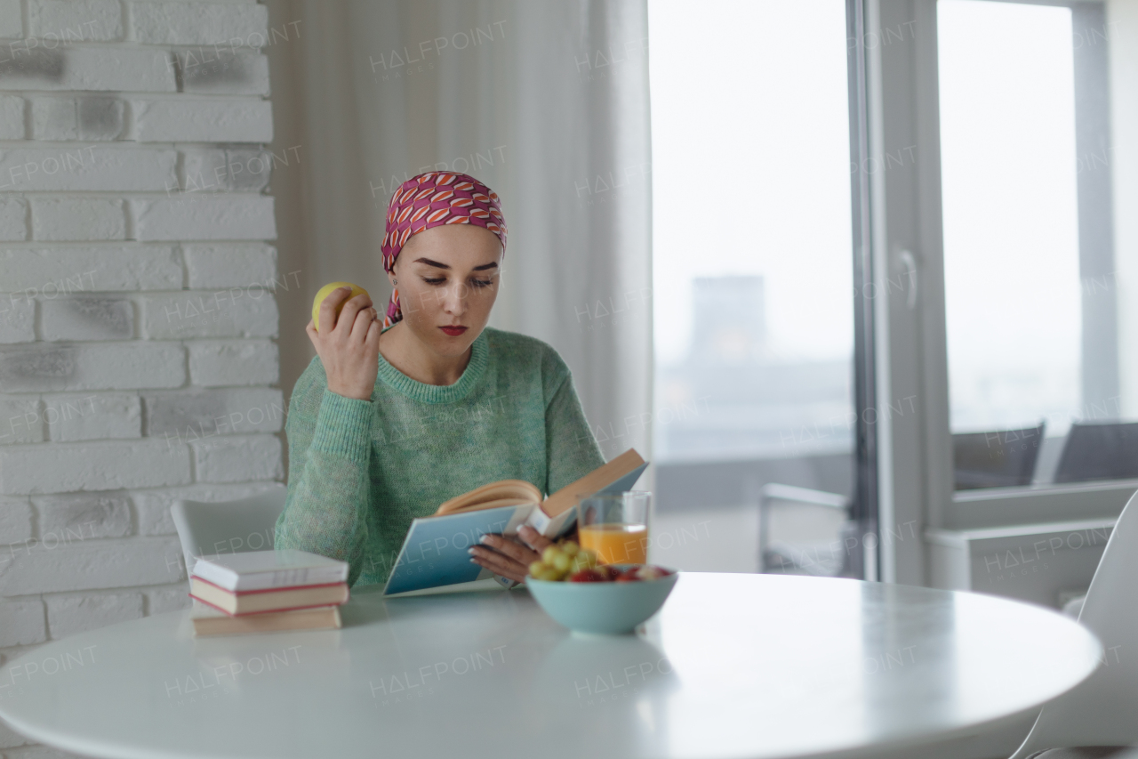 Young woman with cancer reading a book, cancer awareness concept.