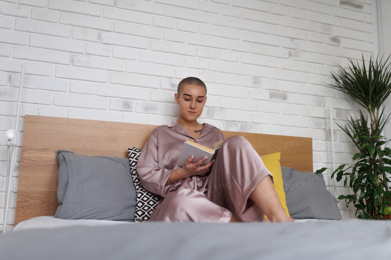 Young woman with cancer reading a book, cancer awareness concept.