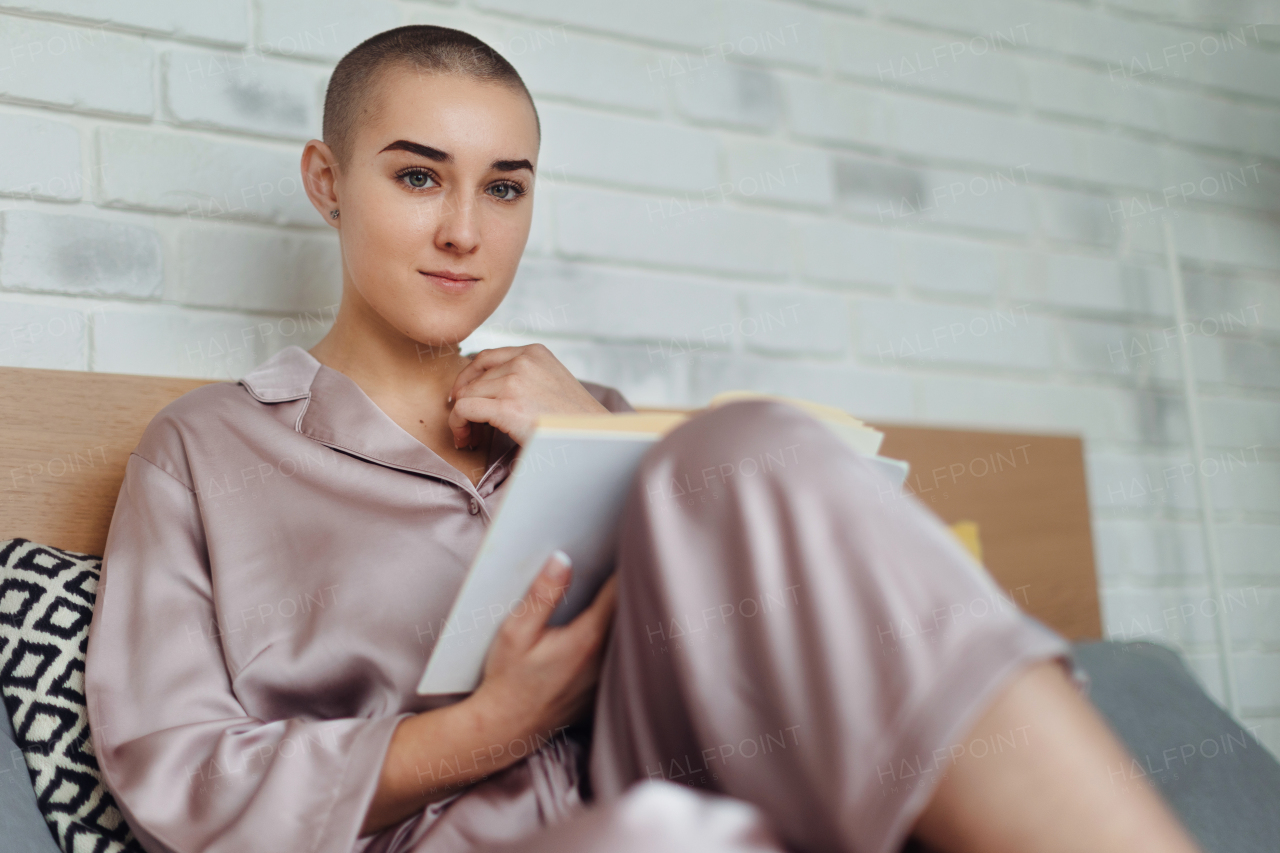 Young woman with cancer reading a book, cancer awareness concept.