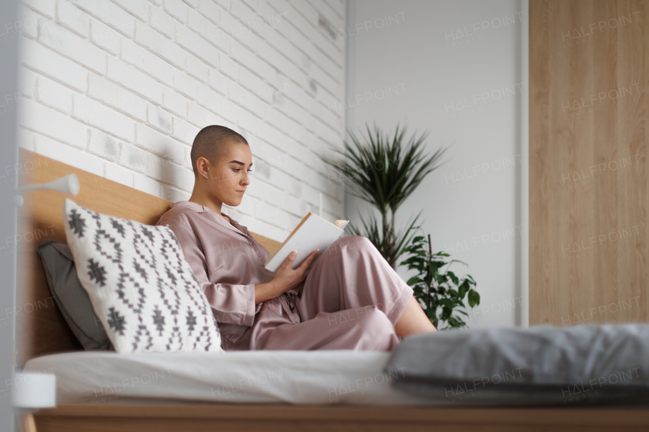 Young woman with cancer reading a book, cancer awareness concept.