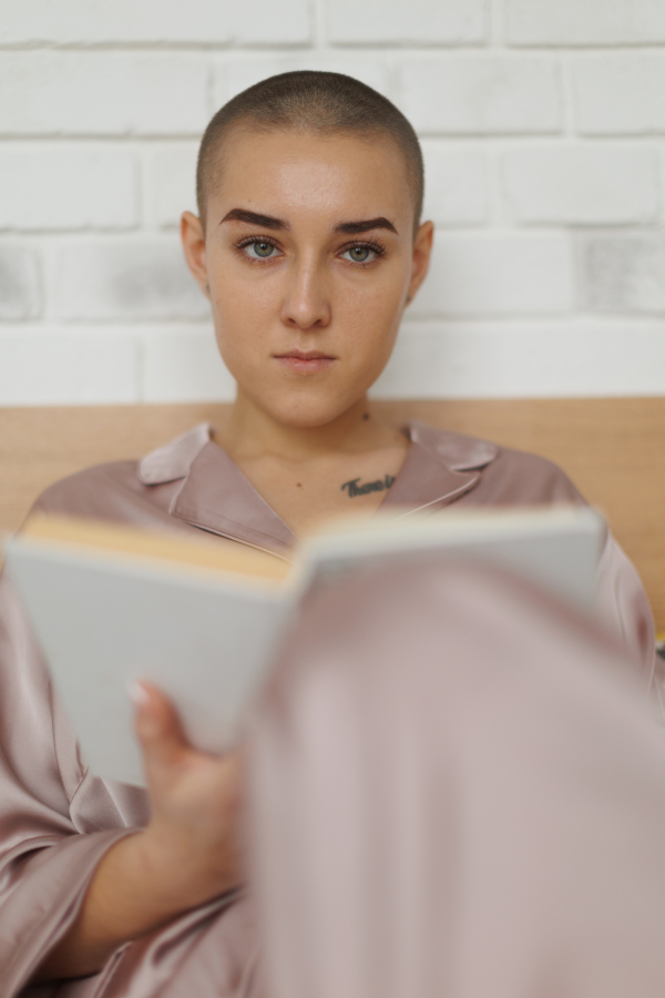 Portrait of young woman with cancer reading a book, cancer awareness concept.